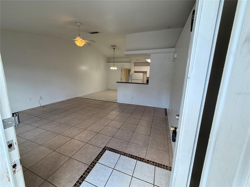 An interior view shows a tiled living area leading to a kitchen with a breakfast bar — 9515 SW 31ST COURT, OCALA, FL