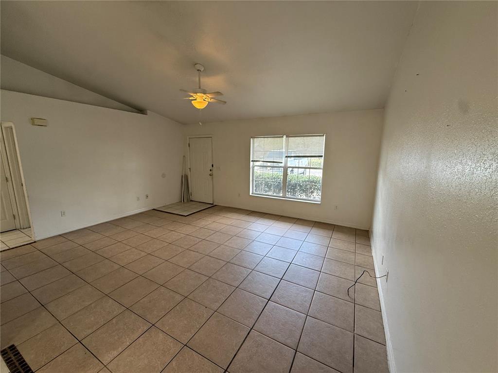 An empty room features beige tile flooring, white walls, a ceiling fan, and a window — 9515 SW 31ST COURT, OCALA, FL
