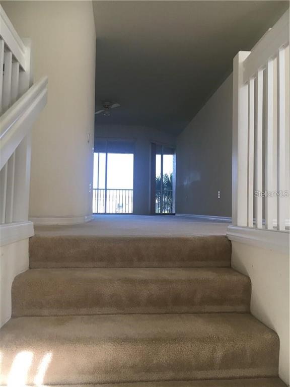 A carpeted staircase leads up to a living area with large windows and a balcony — 4480 STREAMSIDE COURT UNIT 1505, SARASOTA, FL