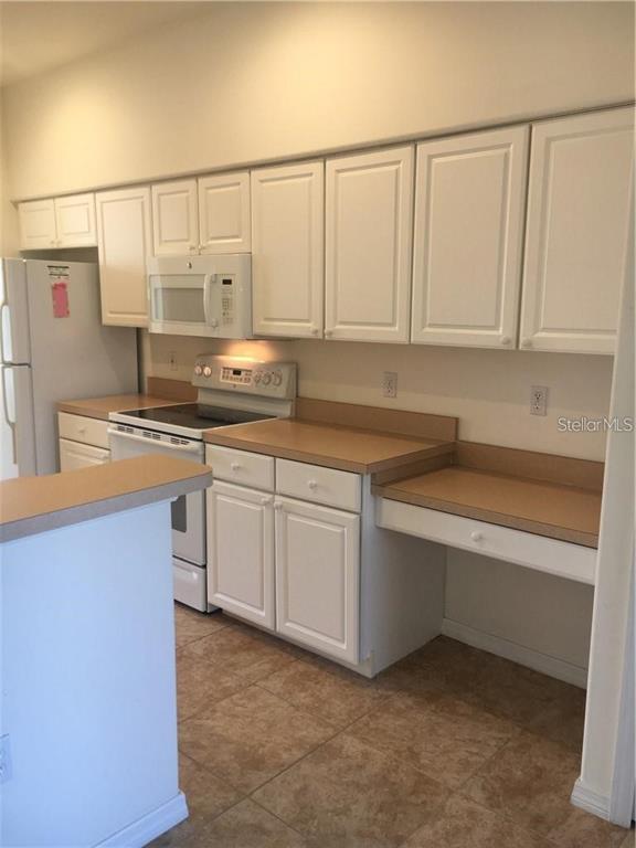 A kitchen features white cabinets, tan laminate countertops, a white stove, and a white refrigerator — 4480 STREAMSIDE COURT UNIT 1505, SARASOTA, FL