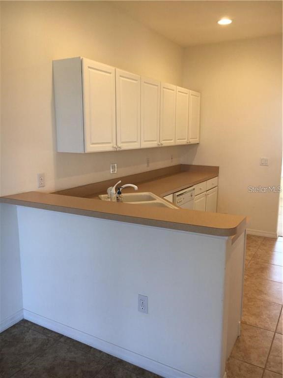 A kitchen features white cabinets, a beige countertop, and a double sink — 4480 STREAMSIDE COURT UNIT 1505, SARASOTA, FL