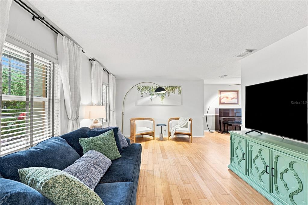 A living room features a blue sofa, a teal media console, and two wooden chairs — 2107 W FORE DRIVE, TAMPA, FL