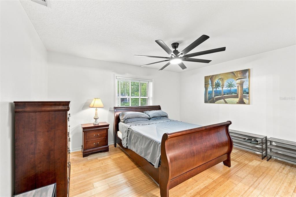 A bedroom features a wooden sleigh bed, a nightstand with a lamp, and a ceiling fan — 2107 W FORE DRIVE, TAMPA, FL