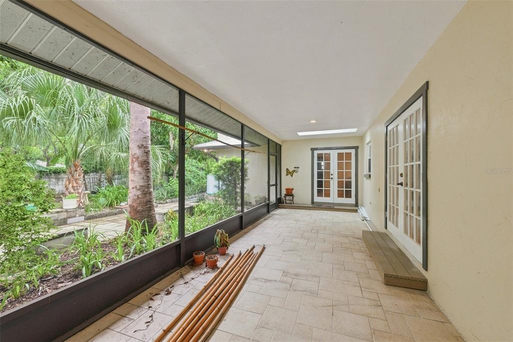 A screened-in patio features tiled flooring, two sets of French doors, and a garden view — 2107 W FORE DRIVE, TAMPA, FL
