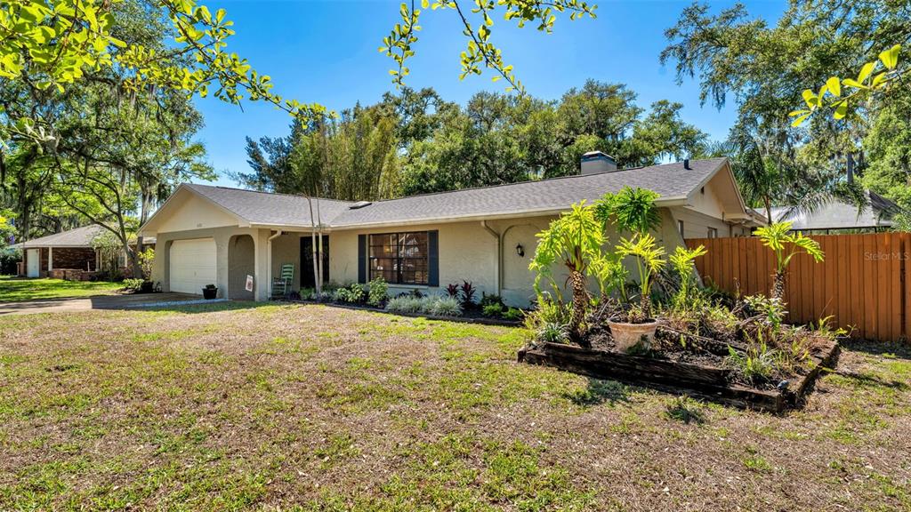A single-story house with a beige exterior, a two-car garage, and a landscaped front yard — 6321 FERN LANE, LAKELAND, FL