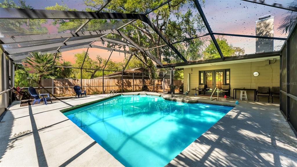 A screened-in swimming pool with a concrete deck and a house exterior in the background — 6321 FERN LANE, LAKELAND, FL