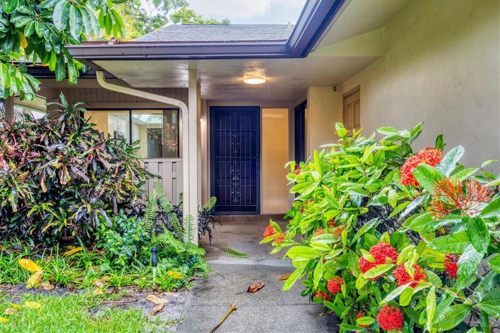 A concrete walkway leads to a covered front entrance with a dark metal security door — 6642 SCHOONER BAY CIRCLE UNIT 6642, SARASOTA, FL