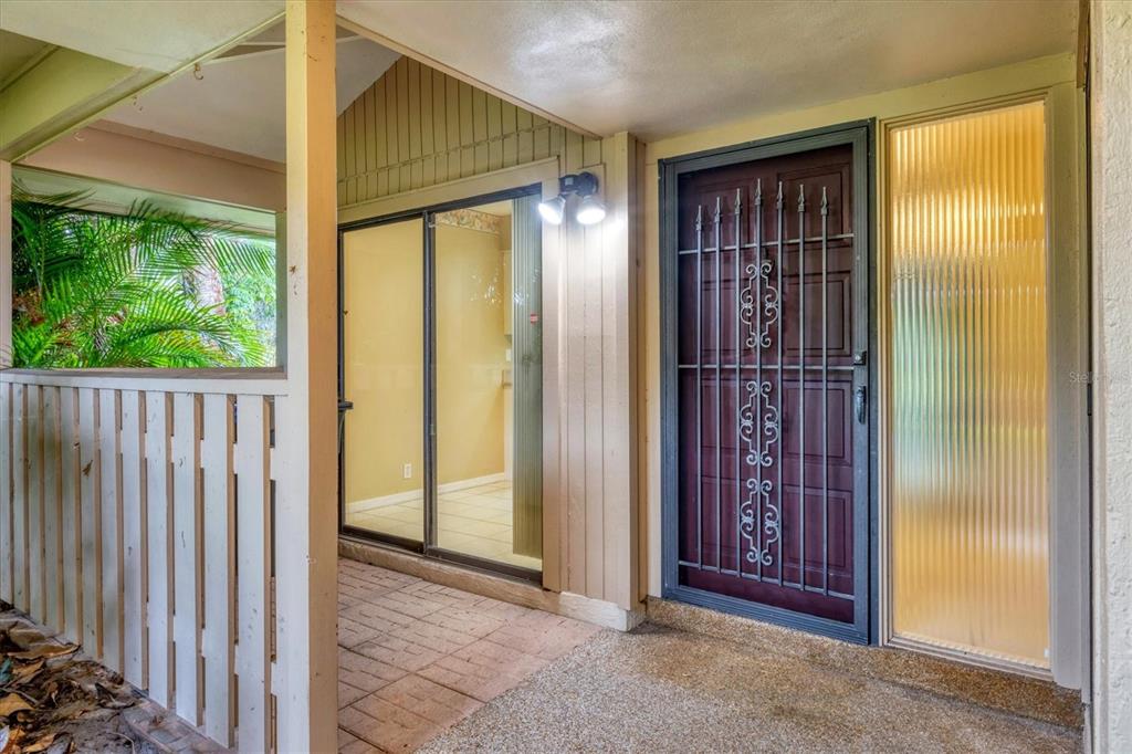 A covered entryway features a brown door with a security gate and a sliding glass door — 6642 SCHOONER BAY CIRCLE UNIT 6642, SARASOTA, FL