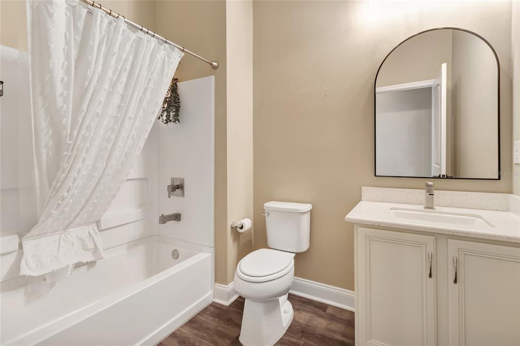 A bathroom features a white vanity, an arched mirror, a toilet, and a shower-tub combination — 549 CHAMPION RIDGE DRIVE, DAYTONA BEACH, FL