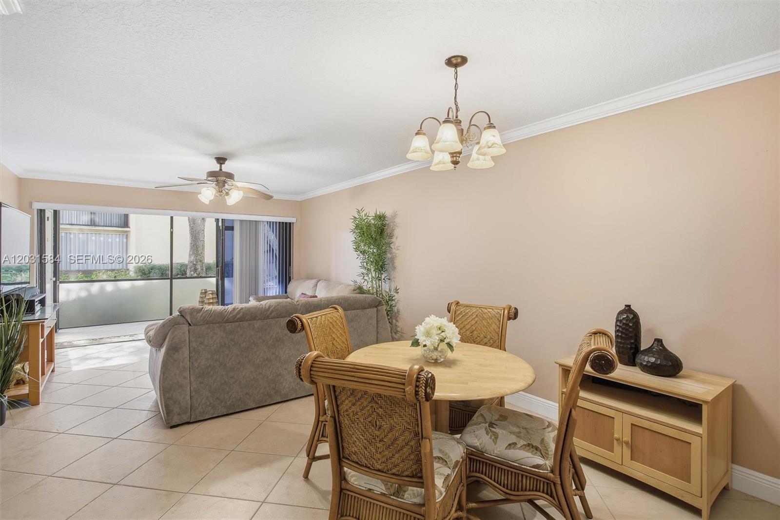 A dining area with wicker chairs and a chandelier sits adjacent to a living room — 2379 SW 15th St # 107, Deerfield Beach FL 33442, DEERFIELD BEACH, FL