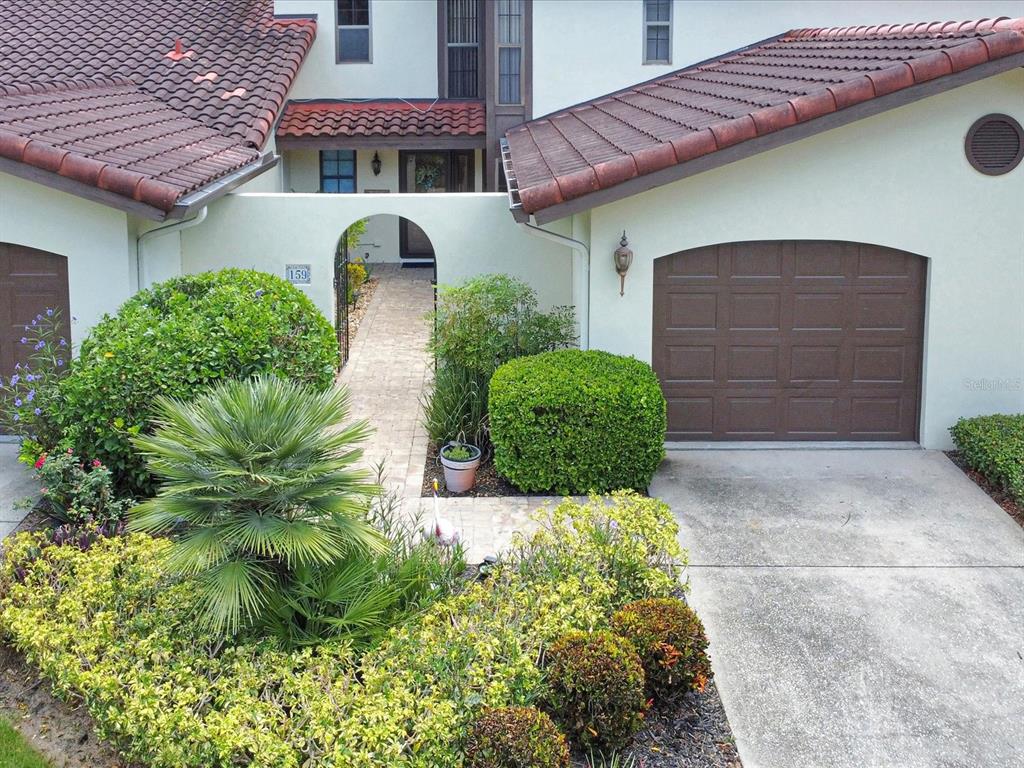 An exterior view of a house with a tiled roof, garage, and a gated courtyard entrance — 159 COVENTRY CIRCLE, HAINES CITY, FL