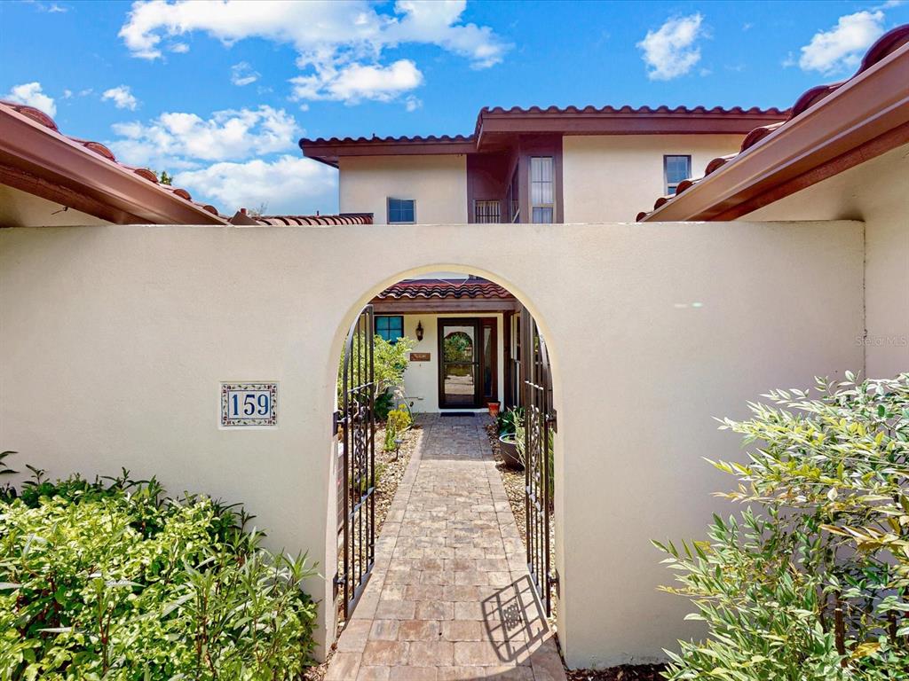 A stone walkway leads through an arched gate to the front entrance of a house — 159 COVENTRY CIRCLE, HAINES CITY, FL