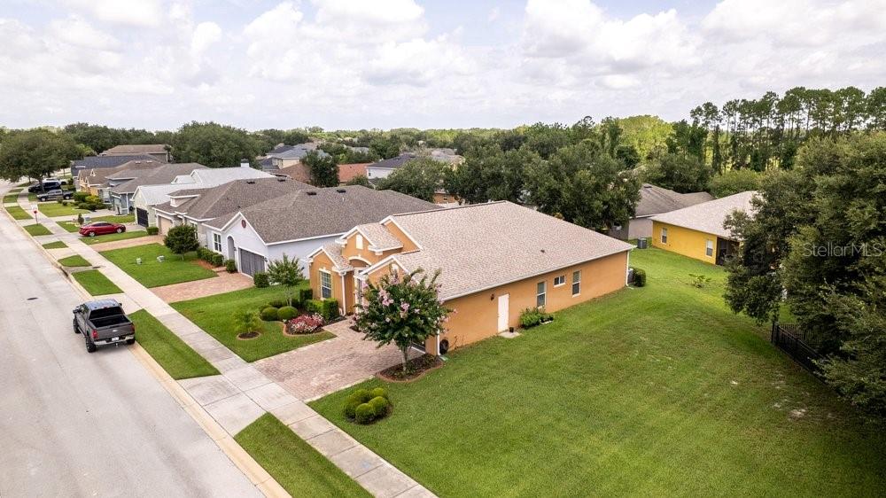 An aerial view shows a suburban street with several single-story houses and green lawns — 5911 WHISPER PINE DRIVE, LEESBURG, FL