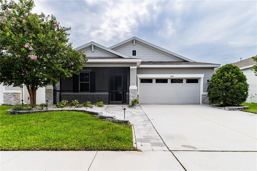 An aerial view shows suburban houses with gray roofs, driveways, and green lawns — 5229 MEADOW SONG DRIVE, OKAHUMPKA, FL