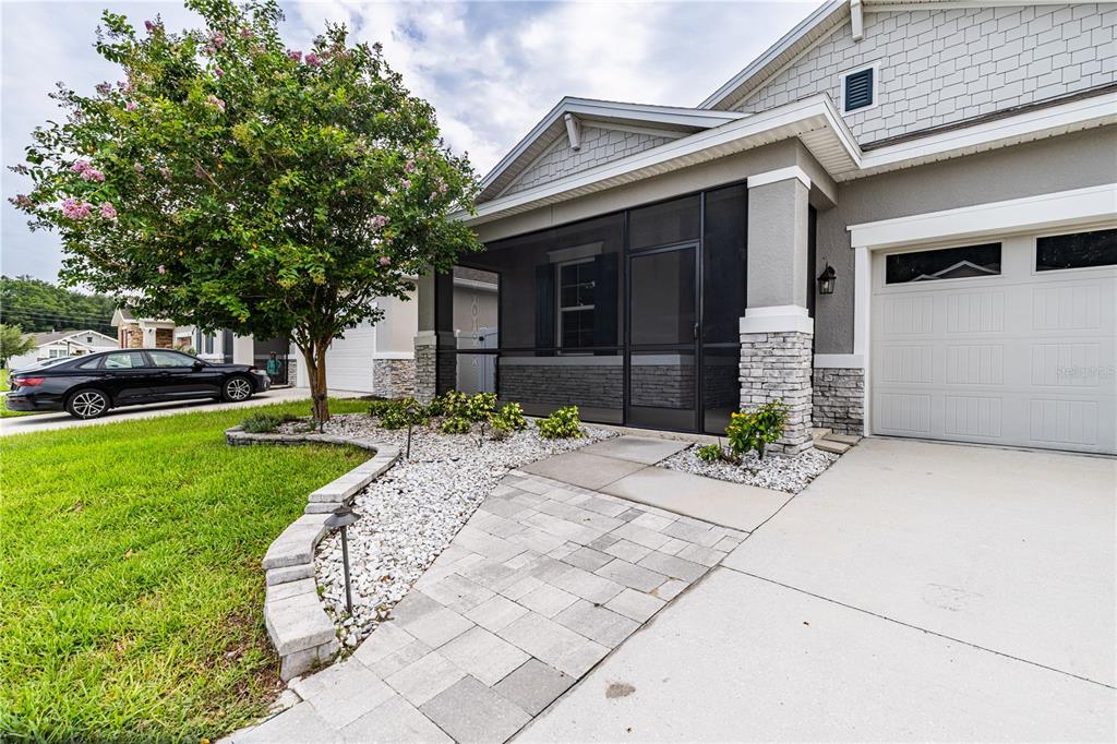 A single-story house features a screened front porch, a two-car garage, and a landscaped yard — 5229 MEADOW SONG DRIVE, OKAHUMPKA, FL