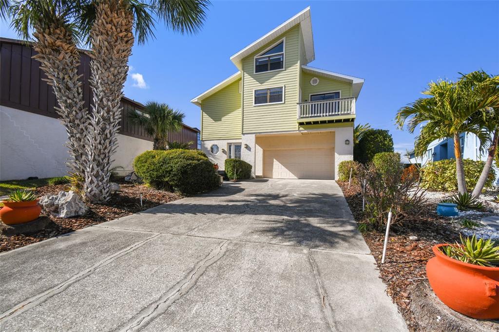 A two-story house with light green siding and a concrete driveway sits under blue skies — 6321 GARLAND COURT, NEW PORT RICHEY, FL