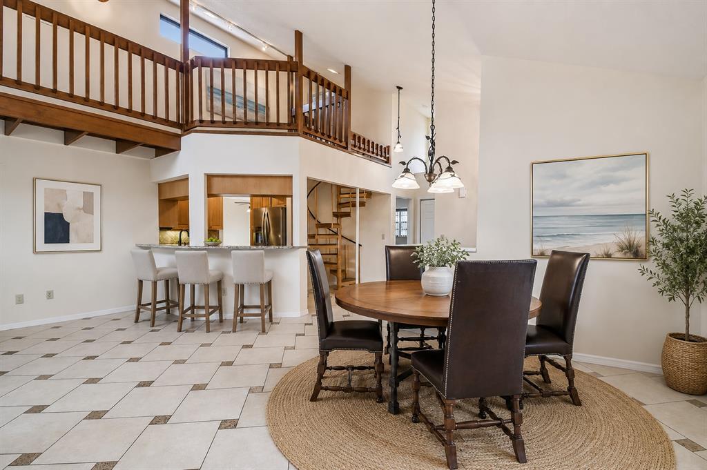A dining area with a round wooden table, leather chairs, and a breakfast bar — 6321 GARLAND COURT, NEW PORT RICHEY, FL
