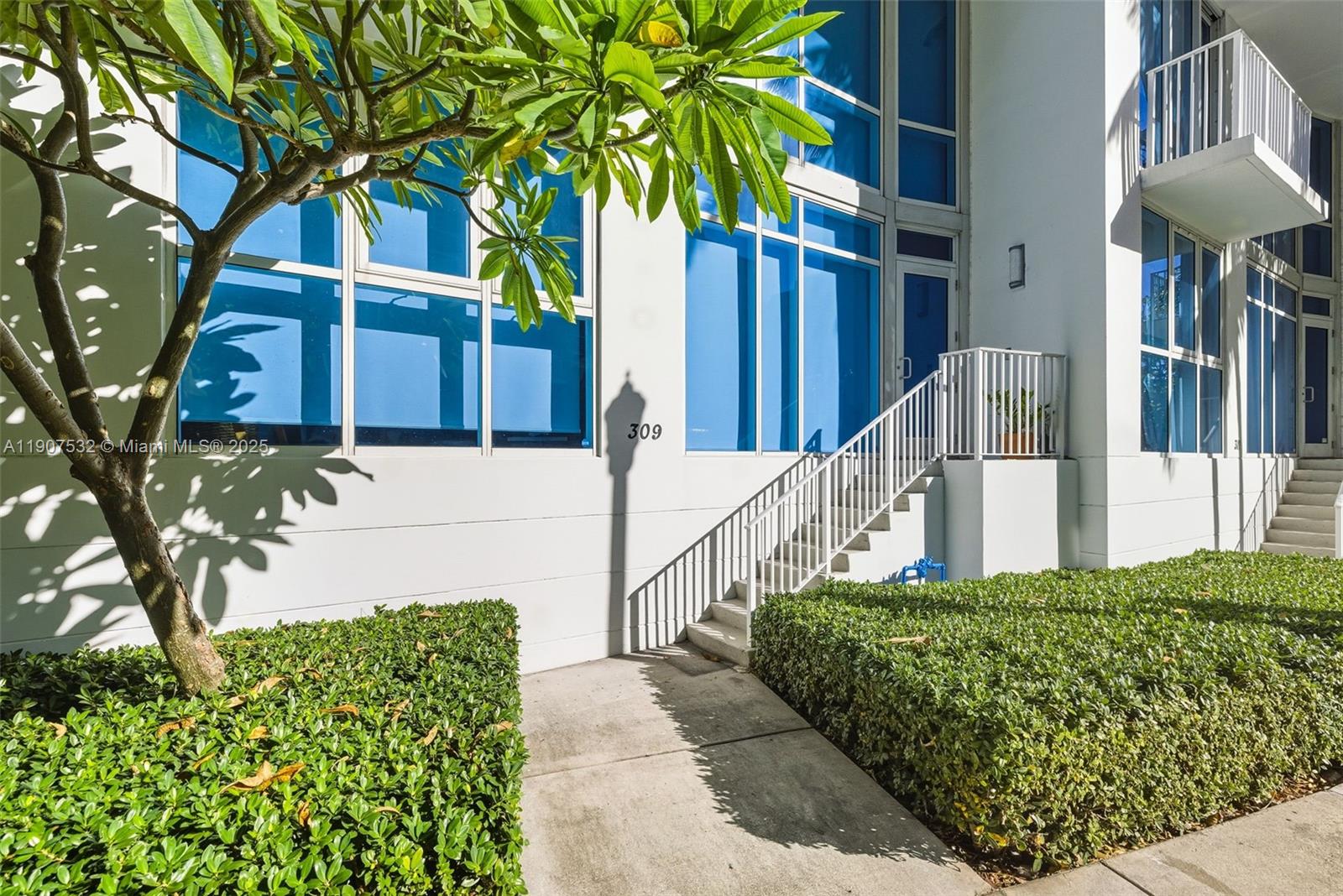 A white building exterior features a staircase leading to a doorway marked with number 309 — 2020 N Bayshore, Miami FL 33137, MIAMI, FL