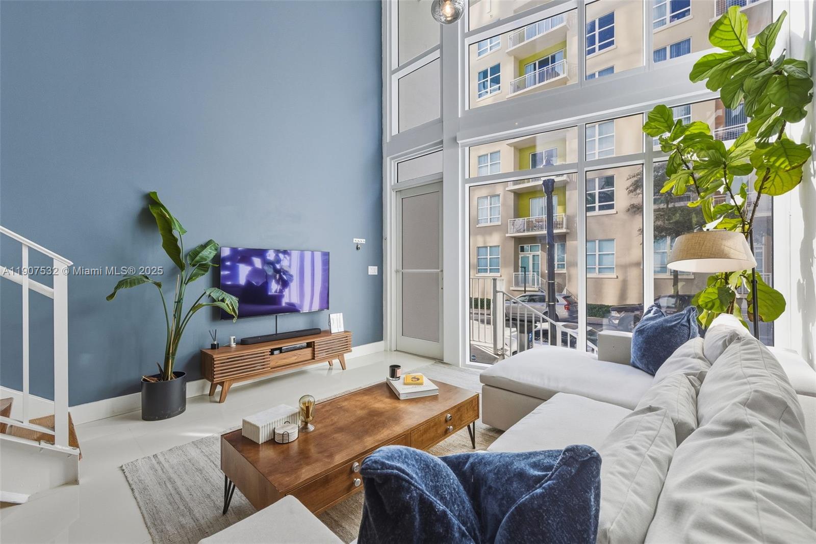 A living room features a blue accent wall, floor-to-ceiling windows, and a wooden coffee table — 2020 N Bayshore, Miami FL 33137, MIAMI, FL