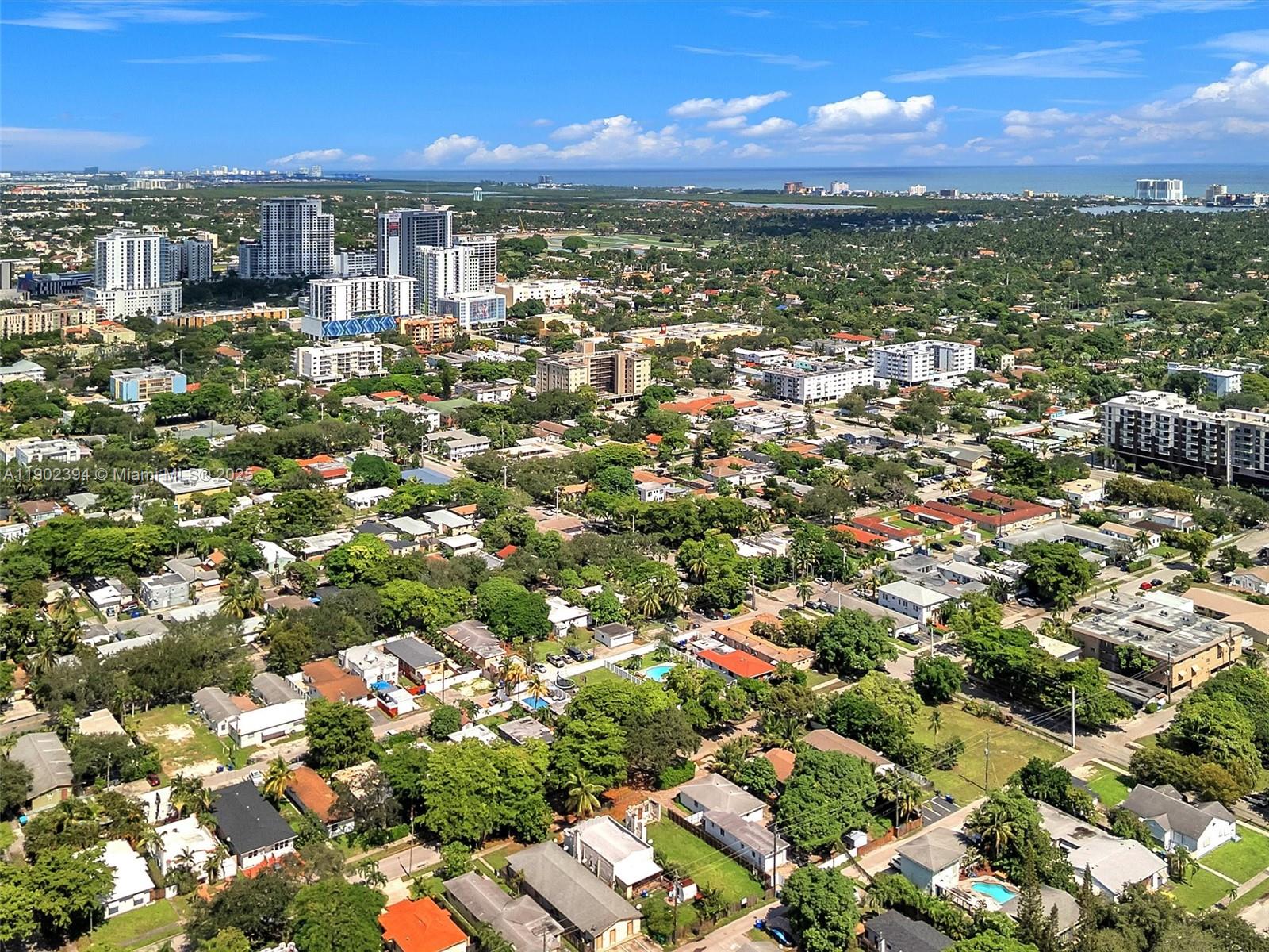 An aerial view shows a suburban neighborhood with houses, trees, and distant high-rise buildings — 1928 Dewey St, Hollywood FL 33020, HOLLYWOOD, FL