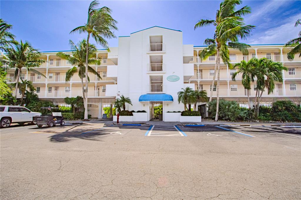 A multi-story white apartment building with balconies and palm trees sits behind a parking lot — 500 BURTON DRIVE UNIT 4204, TAVERNIER, FL