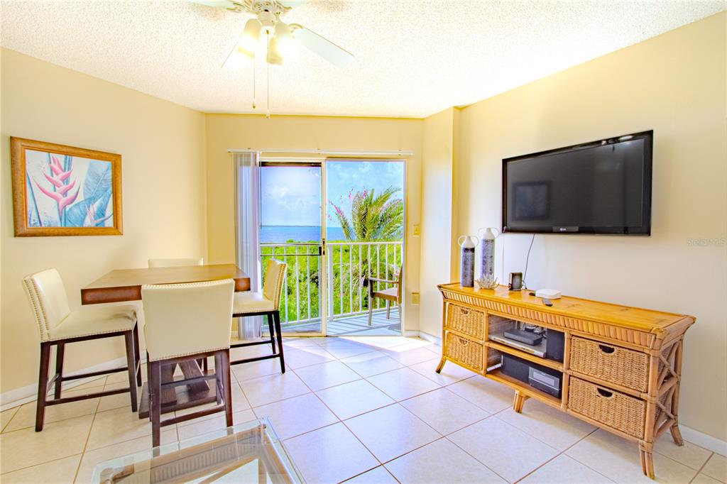 A living and dining area features tile floors, a wicker media console, and a balcony view — 500 BURTON DRIVE UNIT 4204, TAVERNIER, FL