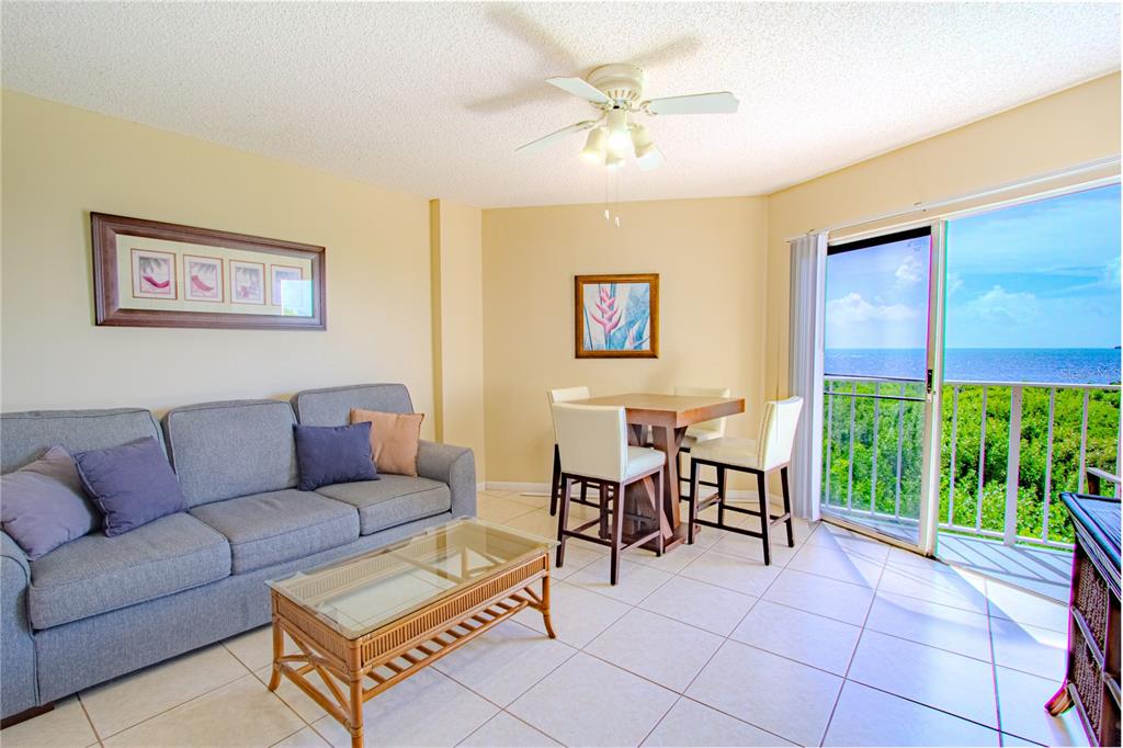 A living and dining area features a gray sofa, glass-topped table, and a balcony view — 500 BURTON DRIVE UNIT 4204, TAVERNIER, FL