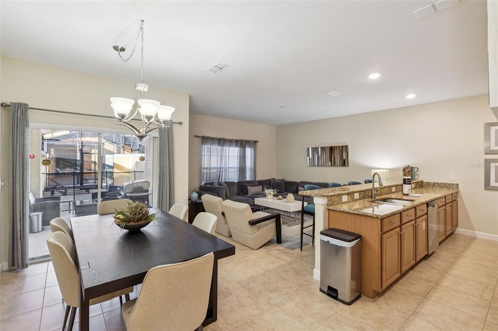 An open-concept kitchen, dining area, and living room with tile floors and granite countertops — 8957 SUGAR PALM ROAD, KISSIMMEE, FL