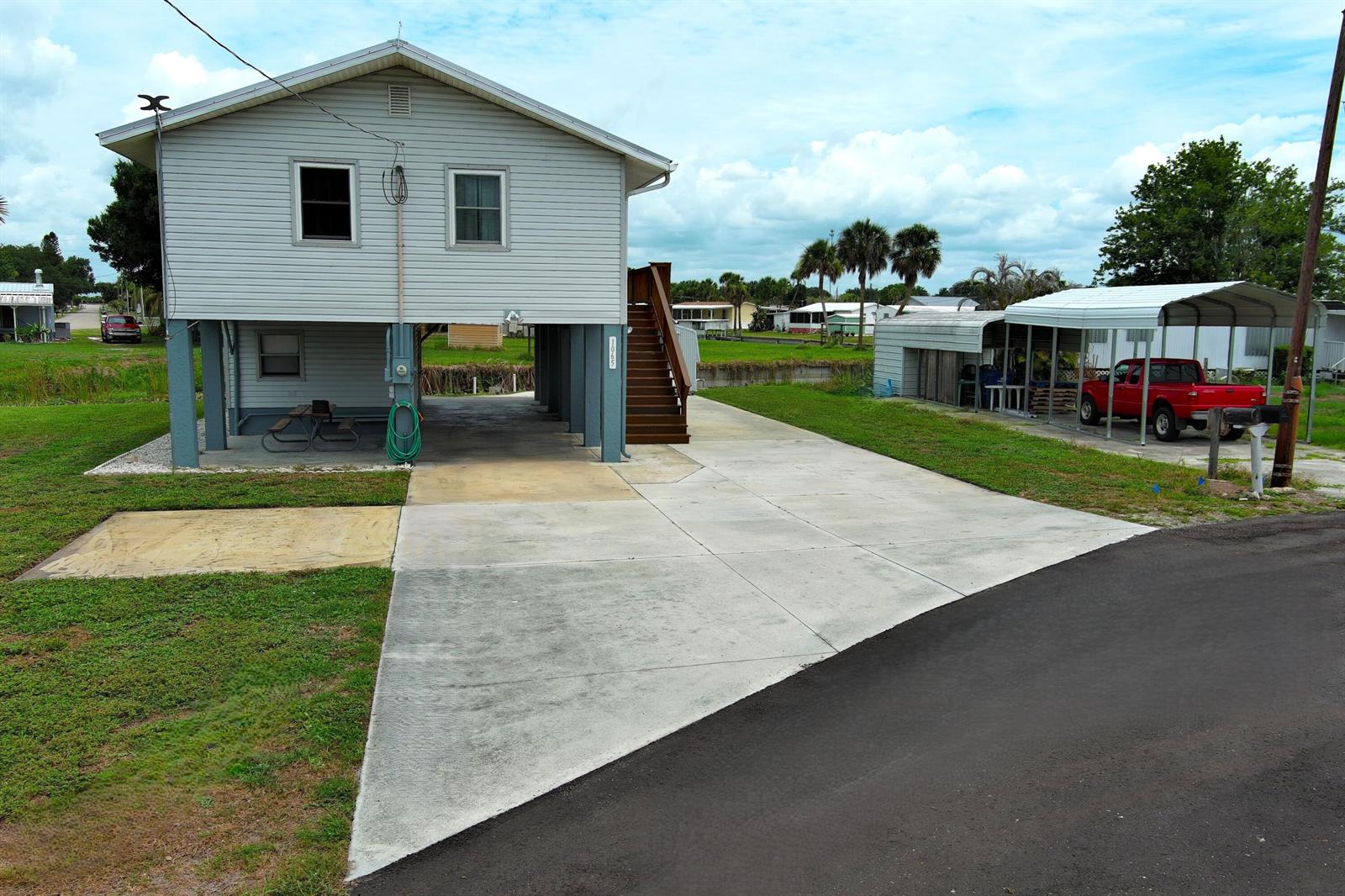 An elevated house with a concrete driveway, a carport, and a red truck parked outside — 1065 Peach Lane, Okeechobee FL 34974, OKEECHOBEE, FL