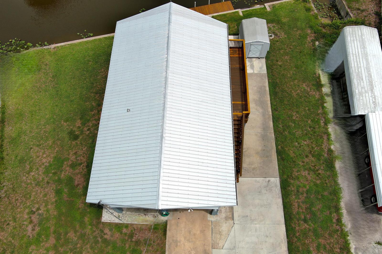 An aerial view shows a house with a metal roof, a wooden deck, and a shed — 1065 Peach Lane, Okeechobee FL 34974, OKEECHOBEE, FL