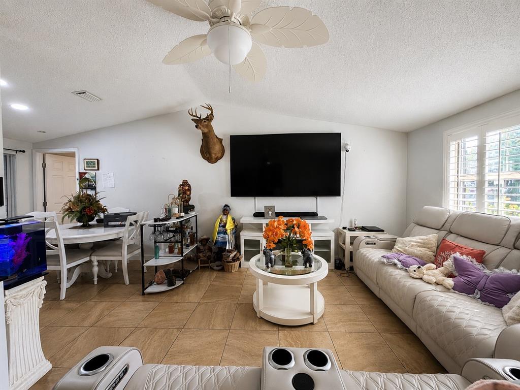 A living room features a large television, a deer mount, and a white sofa — 1341 FOXWOOD DRIVE, LUTZ, FL