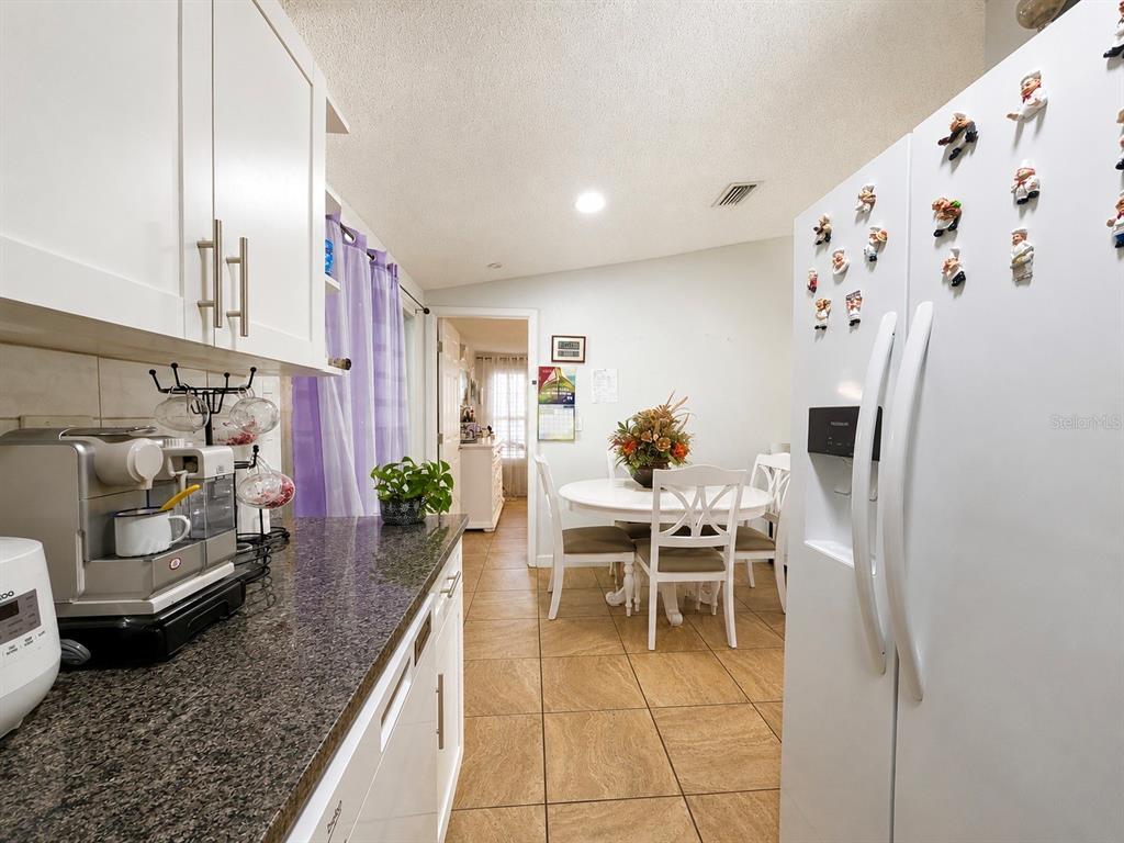 A kitchen with white cabinets, granite countertops, and a dining area with a round table — 1341 FOXWOOD DRIVE, LUTZ, FL