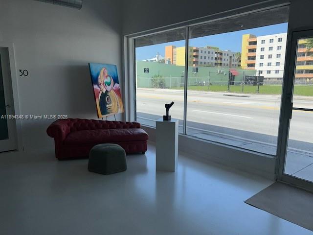 A room with a red tufted sofa, a small stool, and a large window view — 5600 NW 7th Ave, Miami FL 33127, MIAMI, FL
