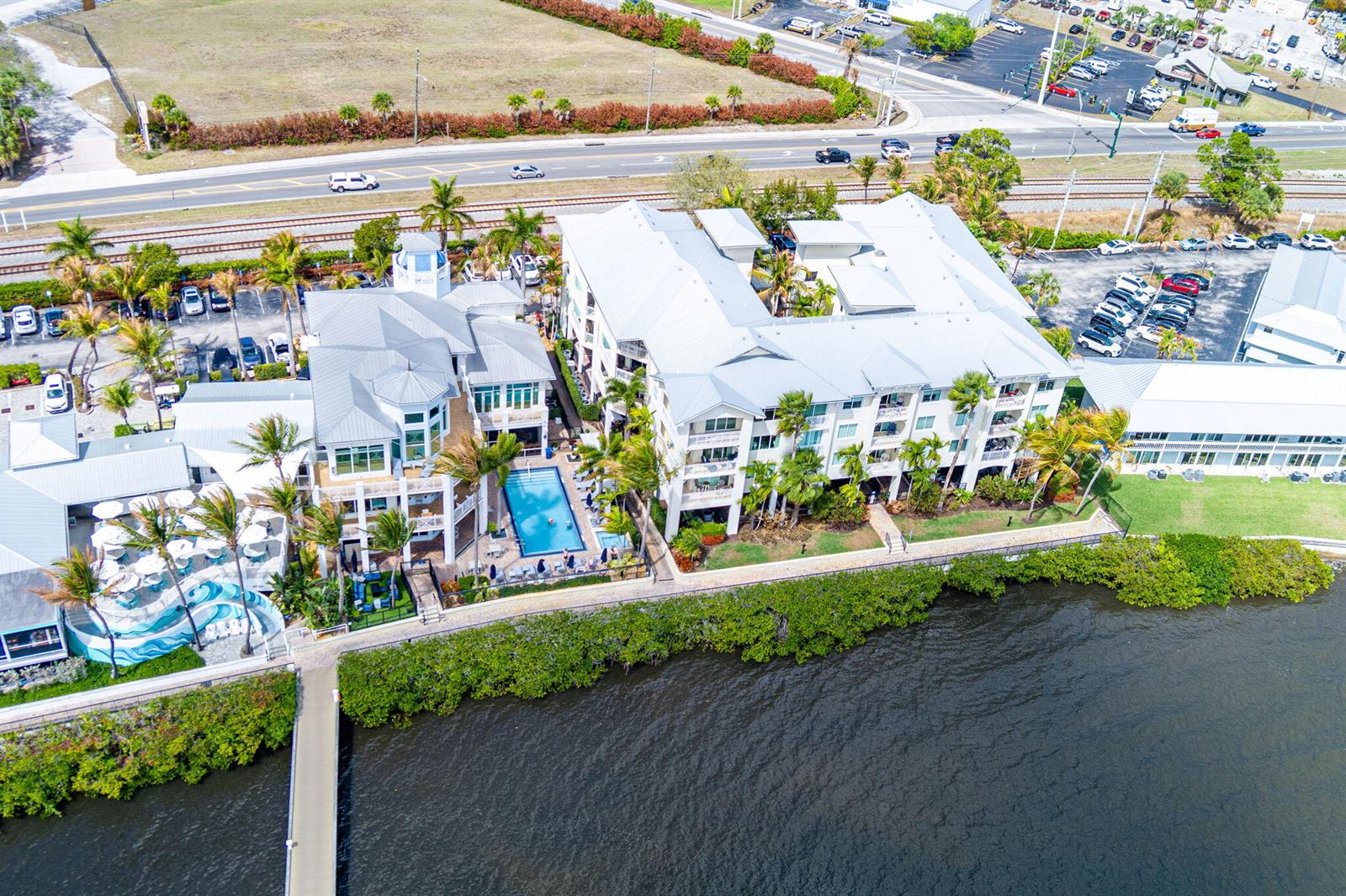 An aerial view shows a waterfront resort complex with a pool, palm trees, and parking — 975 NW Flagler Avenue # 302, Stuart FL 34994, STUART, FL