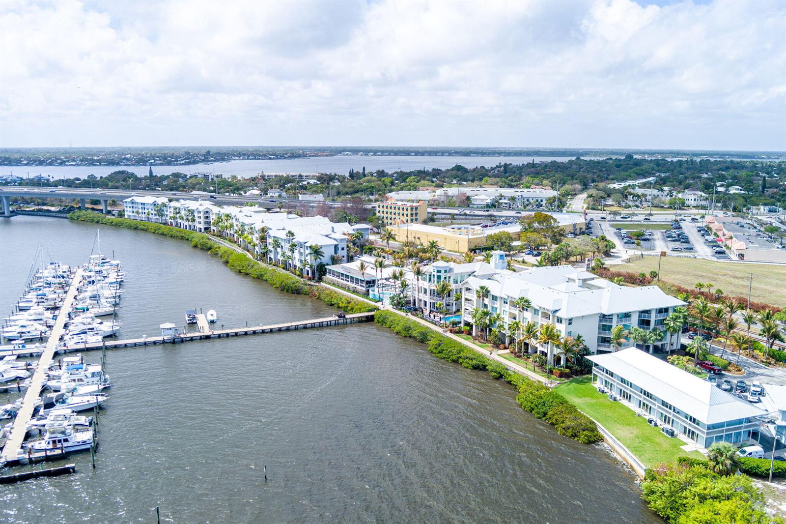 An aerial view shows a waterfront residential complex with a marina and a long pier — 975 NW Flagler Avenue # 302, Stuart FL 34994, STUART, FL