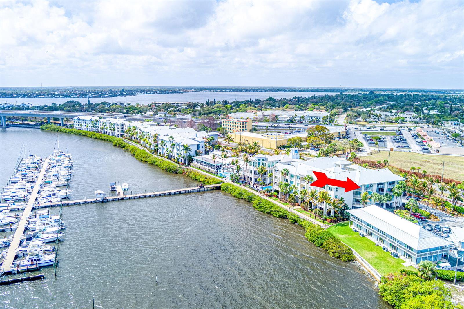 An aerial view shows a waterfront apartment complex with a marina and a red arrow — 975 NW Flagler Avenue # 302, Stuart FL 34994, STUART, FL