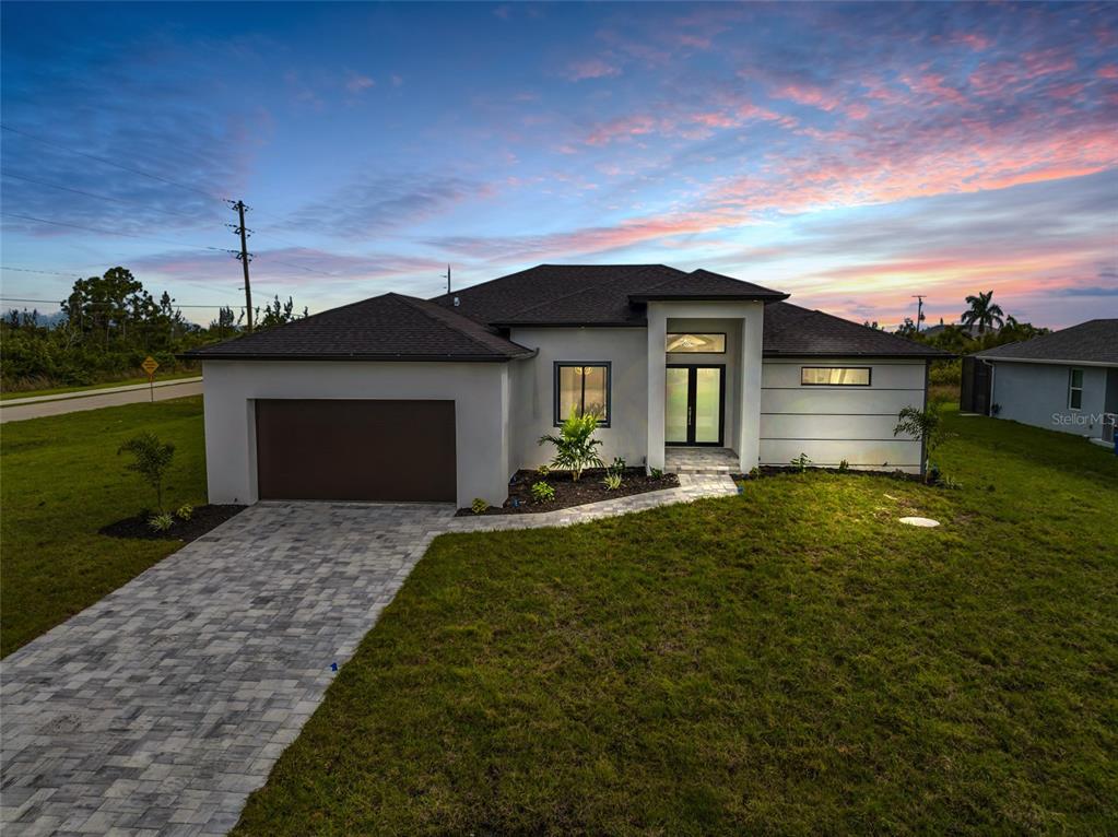 A single-story house with a paved driveway, garage, and front entrance under a sunset sky — 15401 AQUA CIRCLE, PORT CHARLOTTE, FL