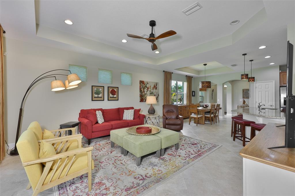 A living room with a red sofa, yellow armchairs, and a dining area beyond — 803 CHIPPER DRIVE, SUN CITY CENTER, FL