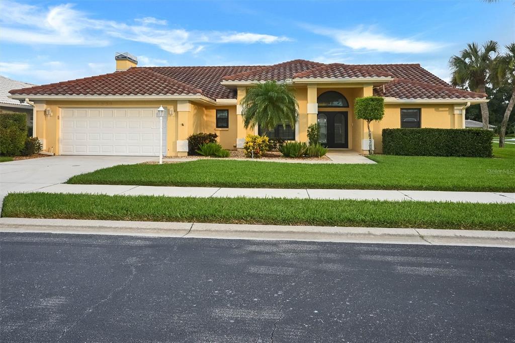 A single-story yellow house with a tile roof, two-car garage, and a manicured front lawn — 1565 WATERFORD DRIVE, VENICE, FL