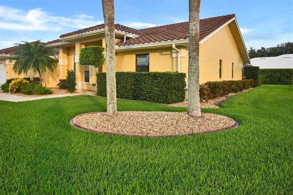 A yellow house with a tile roof, palm trees, and a landscaped lawn — 1565 WATERFORD DRIVE, VENICE, FL