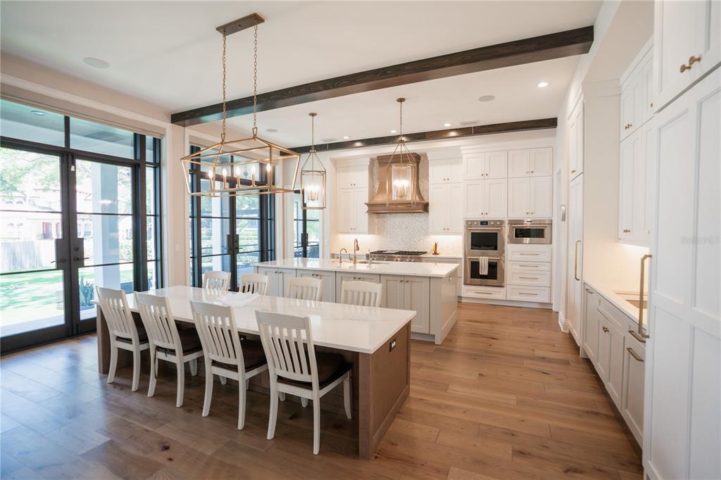 A bright foyer features a double wood door, herringbone wood floors, and a modern chandelier — 4402 W BEACH PARK DRIVE, TAMPA, FL