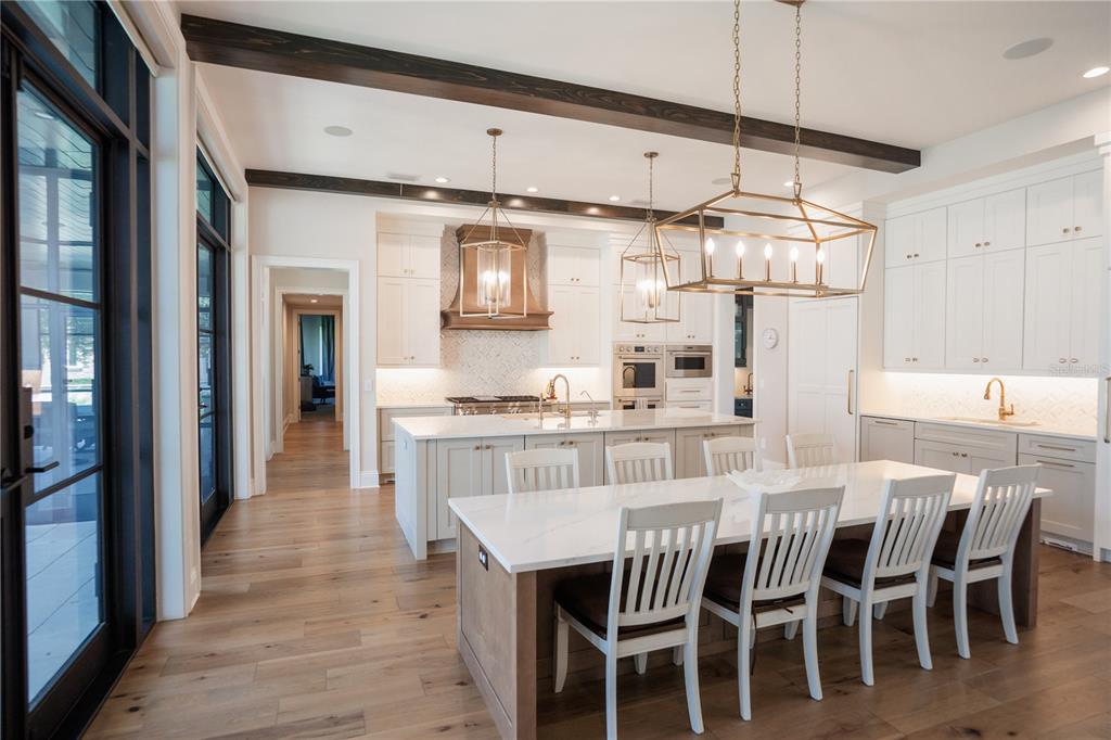 A kitchen features white cabinetry, a wood range hood, and a patterned tile backsplash — 4402 W BEACH PARK DRIVE, TAMPA, FL