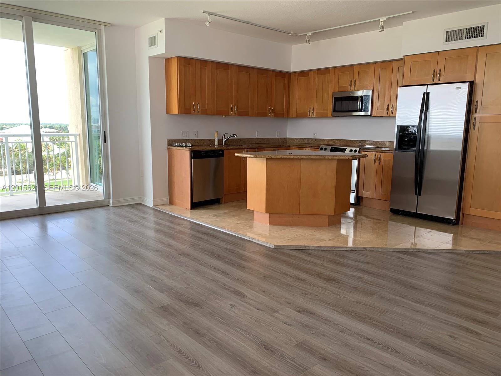 A kitchen with light wood cabinets and stainless steel appliances sits beside a balcony door — 1745 E Hallandale Beach Blvd # 802W, Hallandale Beach FL 33009, HALLANDALE BEACH, FL