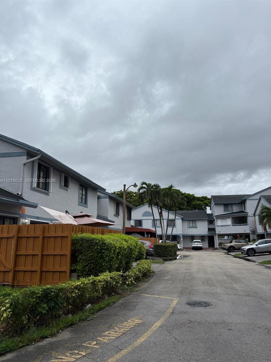 A view of a residential complex parking area with multi-story buildings under a cloudy sky — 1405 SW 122nd Ave # 13, Miami FL 33184, MIAMI, FL