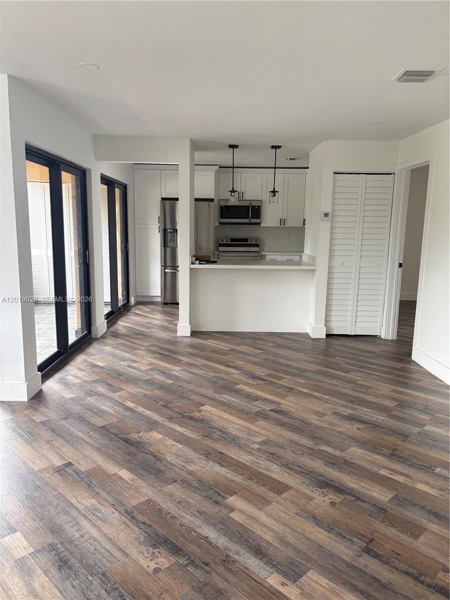 An open-concept kitchen with white cabinets and a breakfast bar overlooks a living area — 1405 SW 122nd Ave # 13, Miami FL 33184, MIAMI, FL