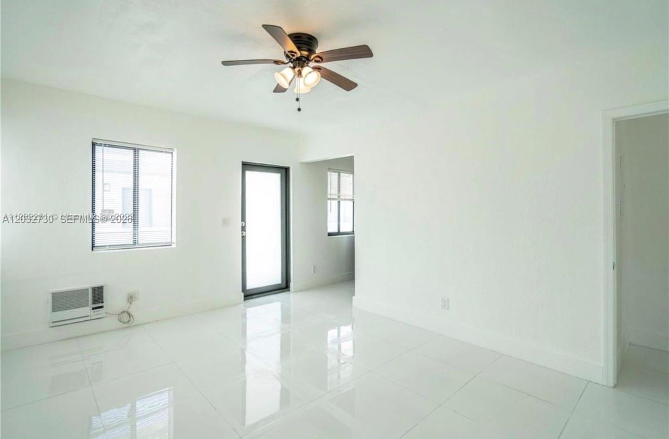 A bright, empty room features white walls, glossy tile floors, and a ceiling fan — 7935 Crespi Blvd # 3, Miami Beach FL 33141, MIAMI BEACH, FL