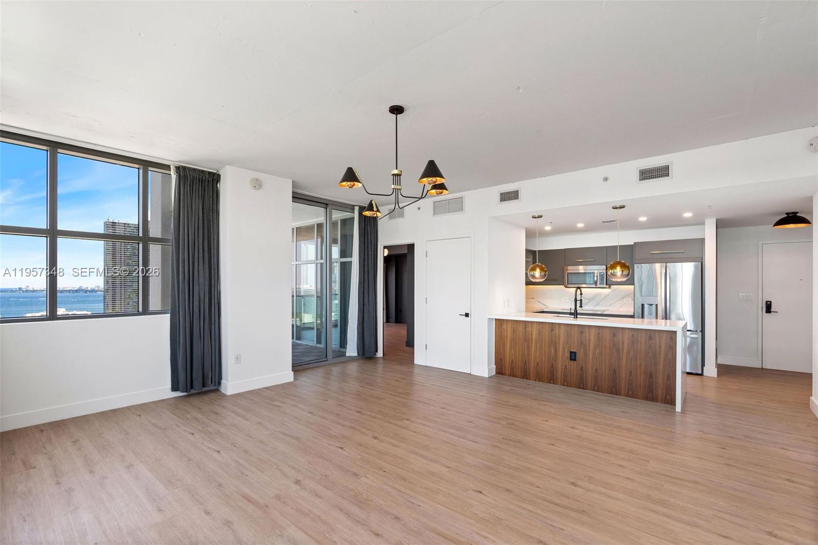 An open-concept living area features wood-look flooring, a modern kitchen, and floor-to-ceiling windows — 3301 NE 1st Ave # H2215, Miami FL 33137, MIAMI, FL