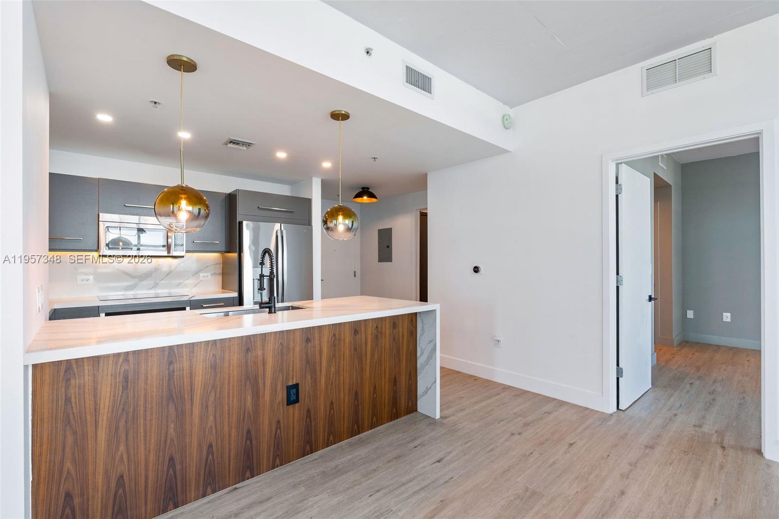 A modern kitchen features a wood-paneled island, white countertops, and dark gray cabinetry — 3301 NE 1st Ave # H2215, Miami FL 33137, MIAMI, FL