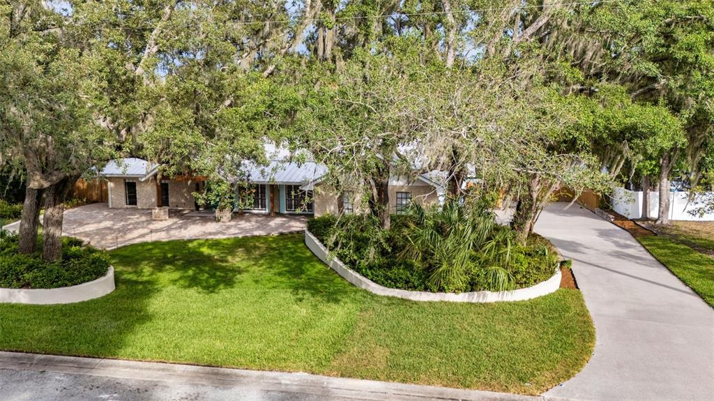 A single-story house with a stone facade, metal roof, and a large landscaped front yard — 11310 DONNEYMOOR DRIVE, RIVERVIEW, FL