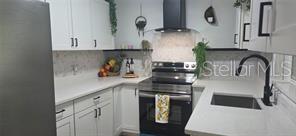 A modern kitchen features white cabinets, stainless steel appliances, a black range hood, and countertops — 1152 NE 9 STREET, OCALA, FL